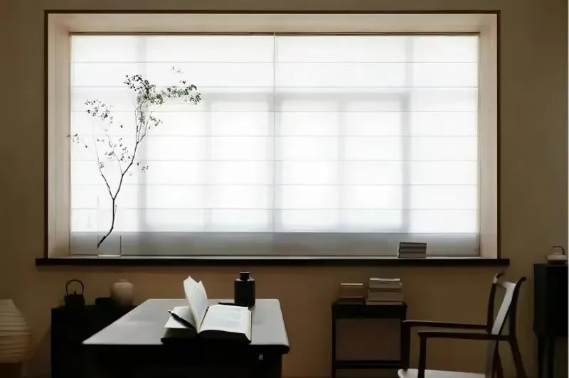 Minimalist study room with wooden desk, open book, decorative vase, and white roman shade on window