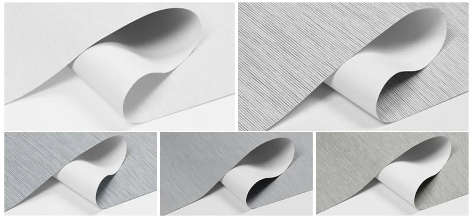 Close-up of curled wallpaper samples with various light grey textured patterns on white backing