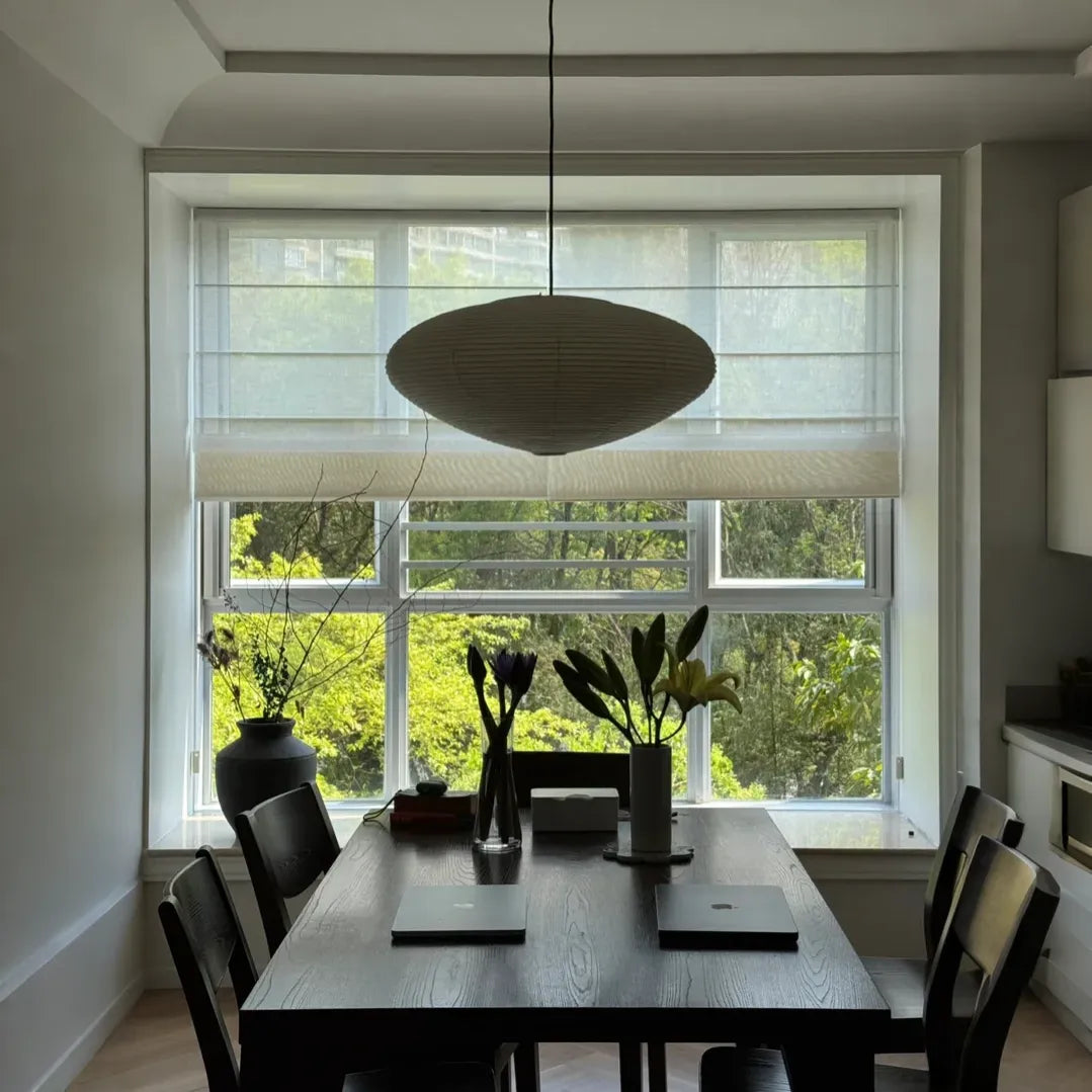 Modern dining room with dark wood table, six chairs, flower vases, and large window with white blinds