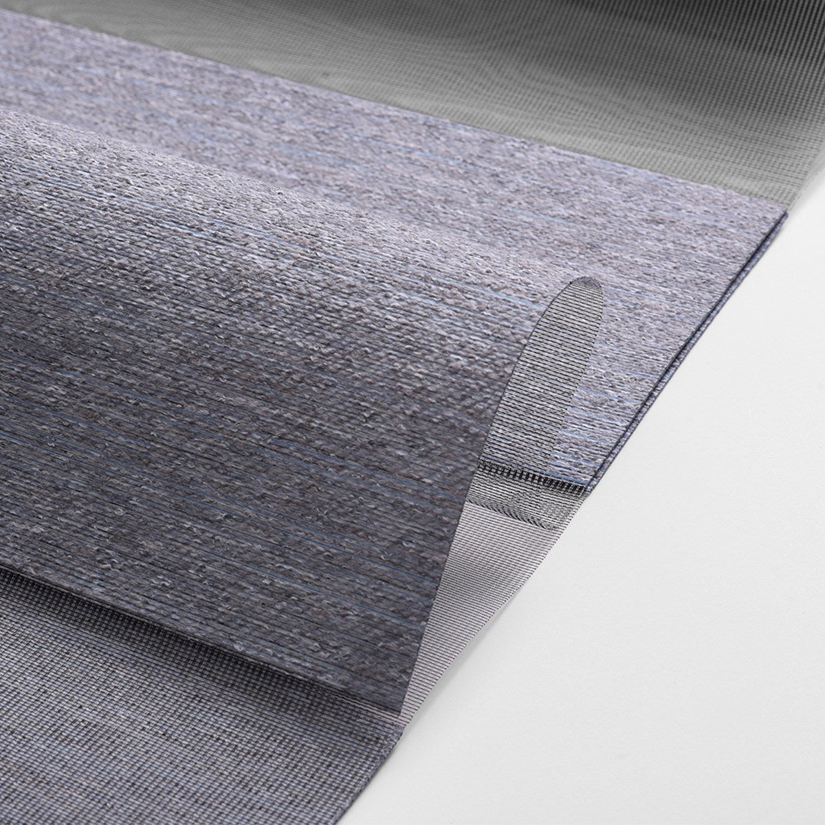 Close-up of blue-gray textured woven rug with folded edge on white background