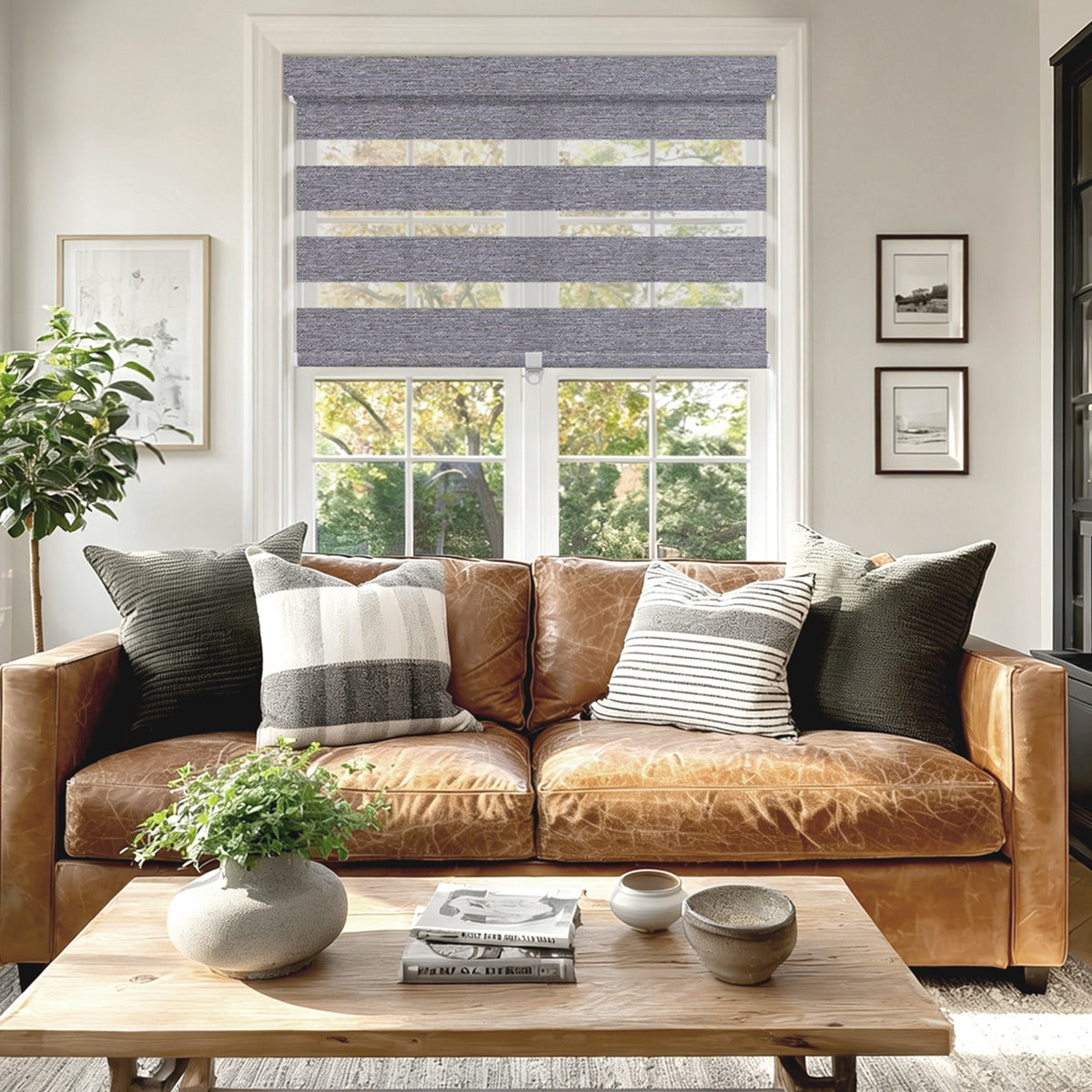 Modern living room with tan leather sofa, striped pillows, wooden coffee table, and gray zebra blinds