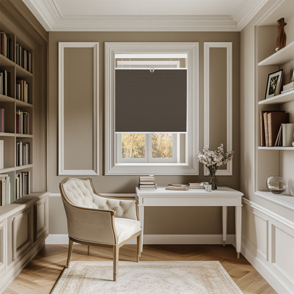 Elegant home office with beige tufted armchair, white desk, dark brown window blind, and built-in bookshelves