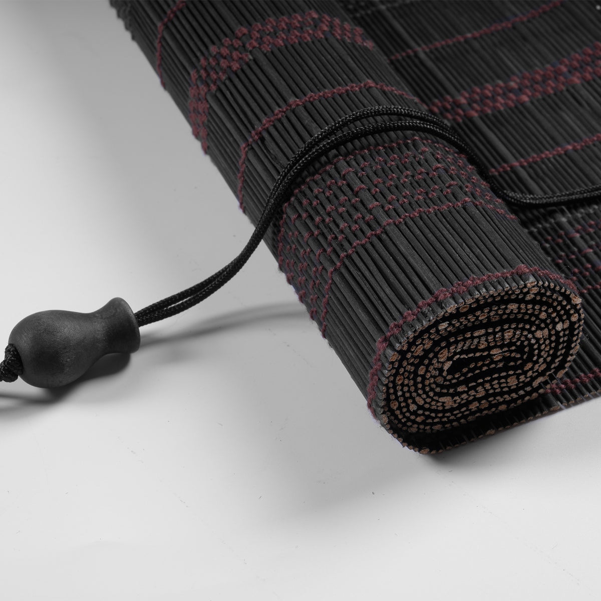 Sulugood Premium Black Hand-Woven Weather Resistant Outdoor Bamboo Shades rolled up with a black cord.