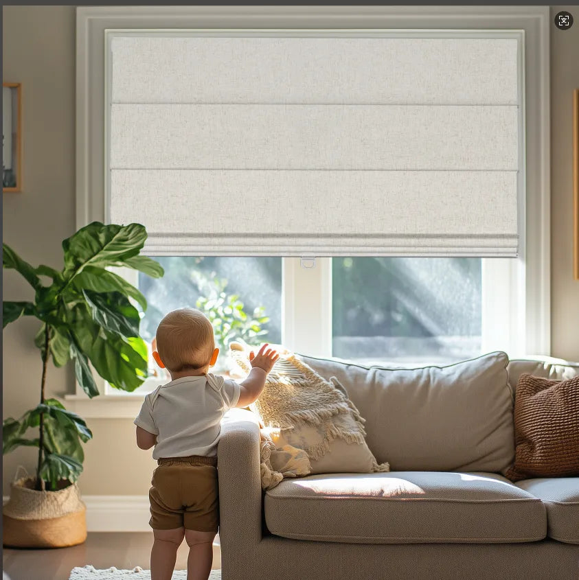 Baby standing by beige sofa near window with white Roman shades and green potted plant in cozy living room