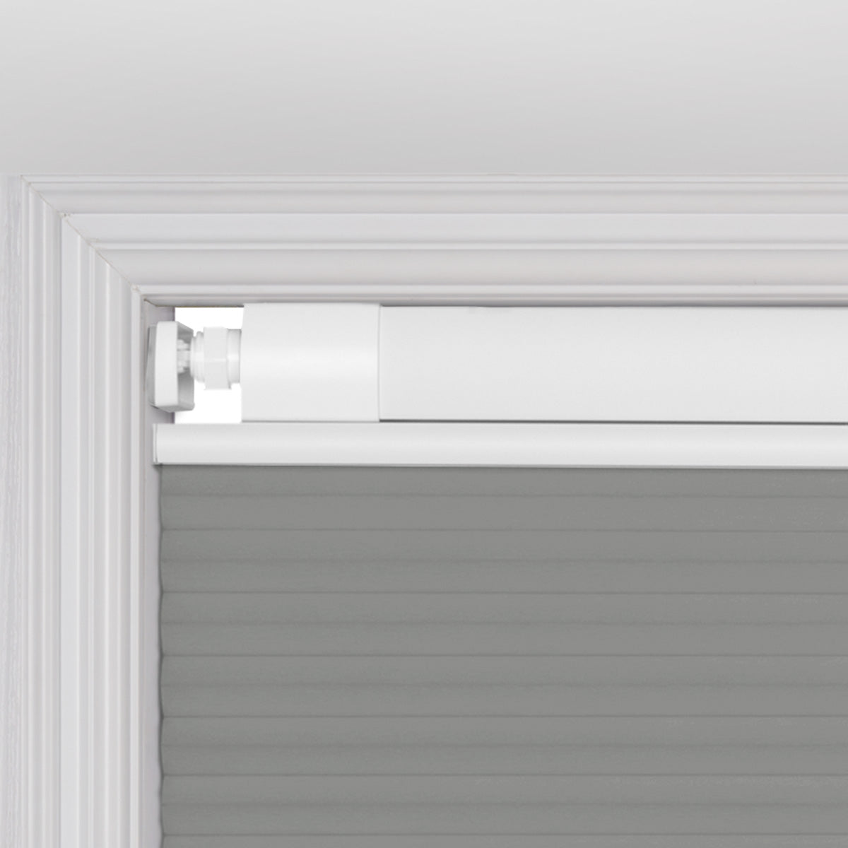 Close-up of a white window frame with installed gray cellular window shade and top mounting bracket