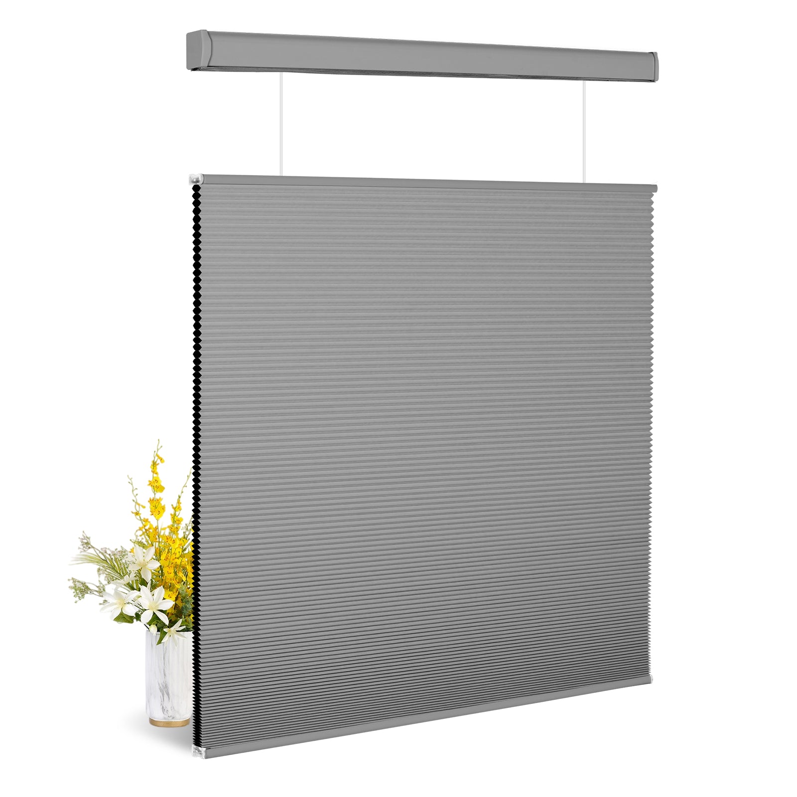 Modern gray cellular window shade with honeycomb texture next to white and yellow flowers in vase