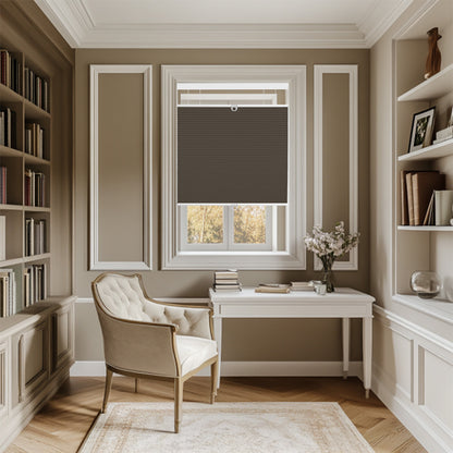 Elegant home office with beige tufted armchair, white desk, dark brown window blind, and built-in bookshelves