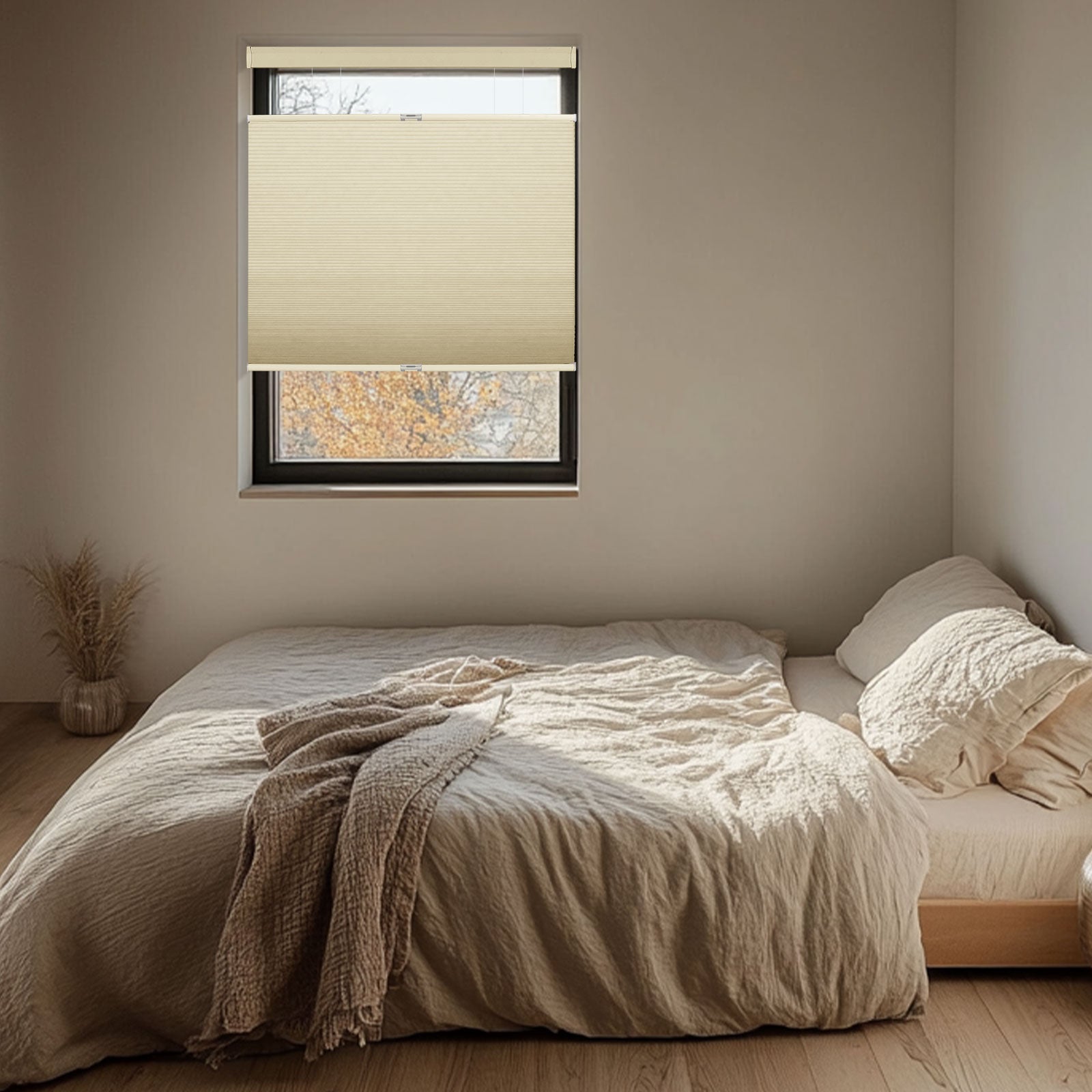 Minimalist bedroom with beige bedding, textured blanket, and half-covered window with beige blind