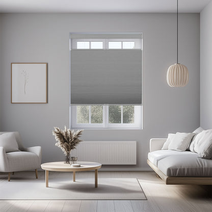 Modern living room with gray cellular window shade, beige sofa, armchair, round wooden coffee table, and hanging light