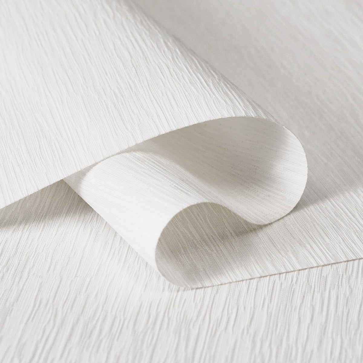 Close-up of white textured wallpaper with subtle vertical lines and curved fold detail