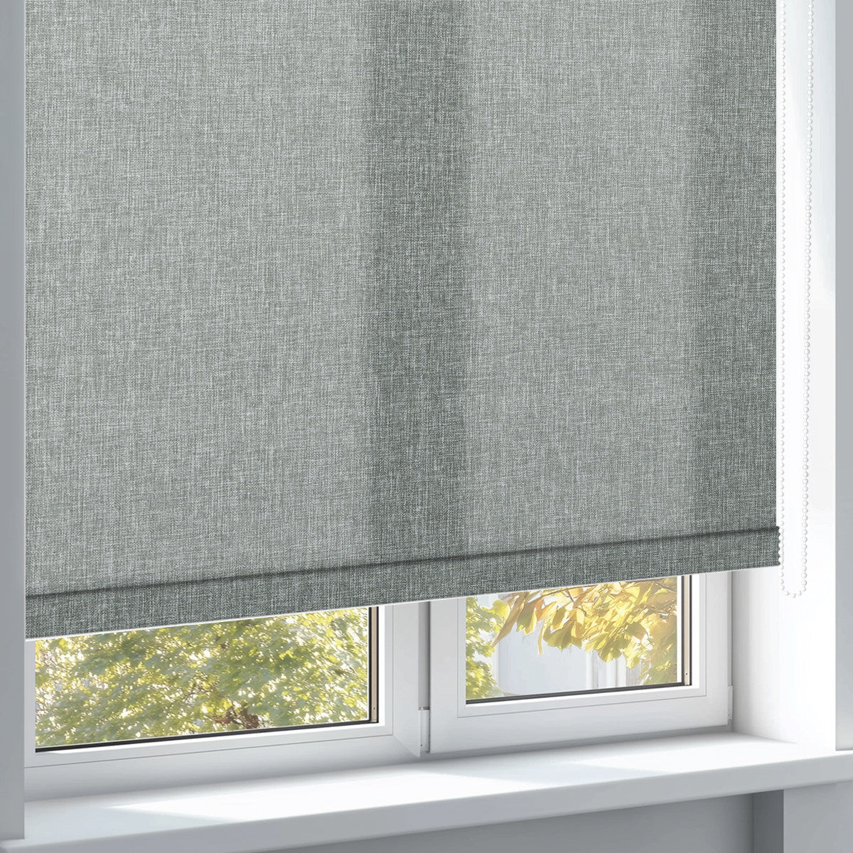 Modern grey textured roller blind partially covering white window with autumn foliage outside