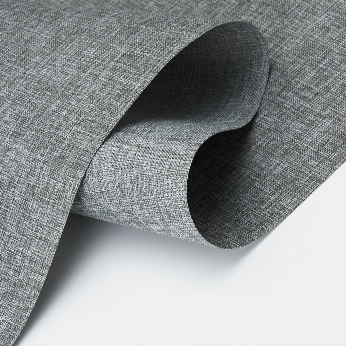 Close-up of curved grey textured vinyl wallpaper sample on white surface